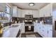 Modern kitchen with white cabinets, stainless steel appliances, and dark tile backsplash at 1040 Hoover Ave, Fort Lupton, CO 80621