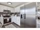 Modern kitchen with white cabinets, stainless steel appliances, and dark tile backsplash at 1040 Hoover Ave, Fort Lupton, CO 80621