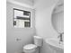 Well-lit powder room with a modern toilet, sink, mirror, and black trimmed window at 2032 S Holly St # 3, Denver, CO 80222