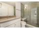 Bathroom featuring tiled shower with glass surround, vanity sink, and toilet at 2032 S Holly St # 3, Denver, CO 80222
