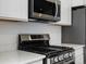 Close up of gas range with microwave and white quartz countertops at 2032 S Holly St # 3, Denver, CO 80222
