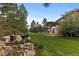 Expansive backyard with lush landscaping, stone patio, and custom fire pit area at 6122 Maroon Peak Pl, Castle Rock, CO 80108