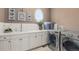 Bright laundry room boasts white cabinetry, modern washer and dryer, and a lovely window at 6122 Maroon Peak Pl, Castle Rock, CO 80108