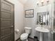 A half bathroom with a pedestal sink, toilet, and gray accents at 11659 W 44Th Ave, Wheat Ridge, CO 80033