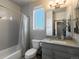 Well-lit bathroom boasts a shower-tub combo, gray vanity, and a window at 11659 W 44Th Ave, Wheat Ridge, CO 80033