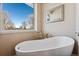 Bright bathroom featuring a modern soaking tub next to a window with a view of trees at 831 Crescent Dr, Boulder, CO 80303