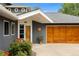 Charming home entrance with wood garage door, stucco walls, and mature plants at 831 Crescent Dr, Boulder, CO 80303
