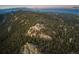 Aerial view of a house nestled in the mountains surrounded by evergreen trees at 13589 Callae Ct, Conifer, CO 80433