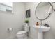 Modern powder room featuring a pedestal sink, round mirror, decorative art, and a toilet at 2052 Alcott Way, Broomfield, CO 80023