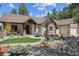 Inviting home exterior featuring stone accents, a covered porch, and meticulous landscaping at 1151 Kenosha Dr, Larkspur, CO 80118