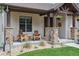 Cozy front porch with stone pillars, wooden chairs, and hanging flower baskets at 1151 Kenosha Dr, Larkspur, CO 80118