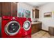 Laundry room with red appliances and wooden cabinets at 1151 Kenosha Dr, Larkspur, CO 80118