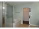 Bright bathroom featuring a soaking tub with tiled surround and glass shower door, plus a closet at 20630 E Hamilton Ave, Aurora, CO 80013