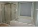 Bright bathroom features a soaking tub with tiled surround, plus a glass shower door at 20630 E Hamilton Ave, Aurora, CO 80013