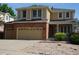 Two-story tan and brick home with a three-car garage, well-manicured lawn, and a cozy covered front porch at 20630 E Hamilton Ave, Aurora, CO 80013