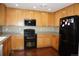 Spacious kitchen featuring wooden cabinets, black appliances, and ample counter space for food preparation at 20630 E Hamilton Ave, Aurora, CO 80013
