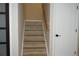 Staircase with light wood steps, a light wood handrail, white walls, and a door with a matte black handle at 20630 E Hamilton Ave, Aurora, CO 80013