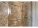 Close-up of glass-enclosed shower featuring travertine tile with decorative inlay and a rainfall shower head at 5455 Landmark Pl # 1403, Greenwood Village, CO 80111