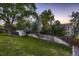 Spacious backyard with lush green grass, a wooden fence, mature trees, and an outbuilding at 7021 S Eudora St, Centennial, CO 80122
