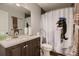 A well-lit bathroom with a dark cabinet, sink, mirror, toilet, shower with dinosaur-themed shower curtain at 7021 S Eudora St, Centennial, CO 80122
