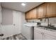 Functional laundry room featuring modern washer and dryer, oak cabinets, ample counter space, and a utility sink at 7021 S Eudora St, Centennial, CO 80122