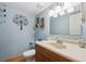 Charming powder room with a wood vanity, decorative mirror, and textured blue walls at 8403 Chase Dr, Arvada, CO 80003