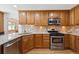 Spacious kitchen features stainless steel appliances, warm wood cabinets, tile backsplash, and granite countertops at 8403 Chase Dr, Arvada, CO 80003