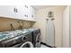 Modern laundry room with front-load washer/dryer and custom cabinets at 8403 Chase Dr, Arvada, CO 80003