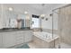 Luxurious bathroom featuring a soaking tub, glass-enclosed shower, and elegant vanity with double sinks and chandelier lighting at 8056 E 35Th Ave, Denver, CO 80238