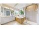 Bright bathroom featuring a soaking tub, a walk-in shower with a glass door, and double vanity at 7597 Bison Ct, Littleton, CO 80125