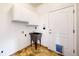 A practical laundry room featuring tiled floors, white cabinets, a utility sink, and a convenient pet door at 7597 Bison Ct, Littleton, CO 80125