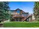 Beautiful backyard with mature trees, deck and stairs leading to a covered patio at 34 Amaranth Dr, Littleton, CO 80127