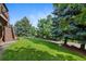 Picturesque backyard featuring a lush lawn, mature trees, and a charming wooden fence, perfect for outdoor enjoyment at 34 Amaranth Dr, Littleton, CO 80127