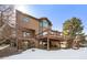 Multi-level deck and backyard of this home during winter, with a backdrop of lush evergreen trees at 34 Amaranth Dr, Littleton, CO 80127