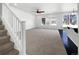 Open living room featuring large windows, neutral carpet, a ceiling fan, and staircase at 1826 Sunshine Ave, Longmont, CO 80504