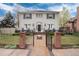 Two-story gray home featuring a black gated fence, front porch, and brick walkway leading to a black front door at 121 N Marion St, Denver, CO 80218