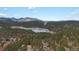 Stunning aerial view showcasing the property's serene setting among lush greenery and a nearby lake at 4786 Forest Hill Rd, Evergreen, CO 80439