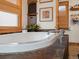 A comfortable bathroom featuring a soaking tub with rock accents, natural light, and wood accents at 4786 Forest Hill Rd, Evergreen, CO 80439