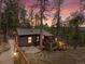 Charming cabin nestled among the trees, featuring a wooden deck and quaint exterior lighting at 4786 Forest Hill Rd, Evergreen, CO 80439
