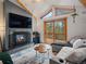 Cozy living room featuring a fireplace, vaulted ceilings, and deck access at 4786 Forest Hill Rd, Evergreen, CO 80439