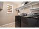 Laundry room featuring black washer and dryer, neutral walls, and storage shelves at 5311 S Danube Ct, Centennial, CO 80015