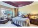 Bedroom with tray ceiling, patterned bedding, sitting area and view to the outside at 16494 Aliante Dr, Broomfield, CO 80023