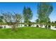 Community's serene pond surrounded by trees, lush grass, and landscaping reflecting in the water at 16494 Aliante Dr, Broomfield, CO 80023
