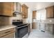 This kitchen includes stainless steel appliances, tiled backsplash, wood cabinets, and granite counters at 6671 Oneida St, Commerce City, CO 80022