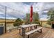A spacious picnic table beneath hanging lights adorns the deck, offering panoramic views and comfortable outdoor dining space at 11549 Haskell Creek Rd, Larkspur, CO 80118
