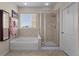 Bright bathroom with a soaking tub, a glass-enclosed shower, and neutral-toned tile work at 15271 Grasslands Dr, Parker, CO 80134