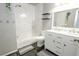 Bright bathroom featuring marble-style tile, shower-tub combo, and updated vanity at 1699 S Trenton St # 69, Denver, CO 80231