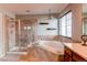Well lit bathroom, soaking tub, glass enclosed shower, tile backsplash, with a decorative chandelier at 463 Mazzini St, Erie, CO 80516