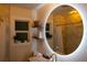 Bright bathroom with round mirror, marble countertop, plants, and a window at 3701 S Grant St, Englewood, CO 80113