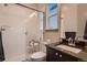 Bright bathroom with glass shower, white tiles, and vanity with dark countertop at 9521 Garnett Way, Arvada, CO 80007